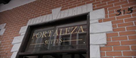 A brick building with a sign that reads "FORTALEZA SUITES" and the number "315" on the wall.