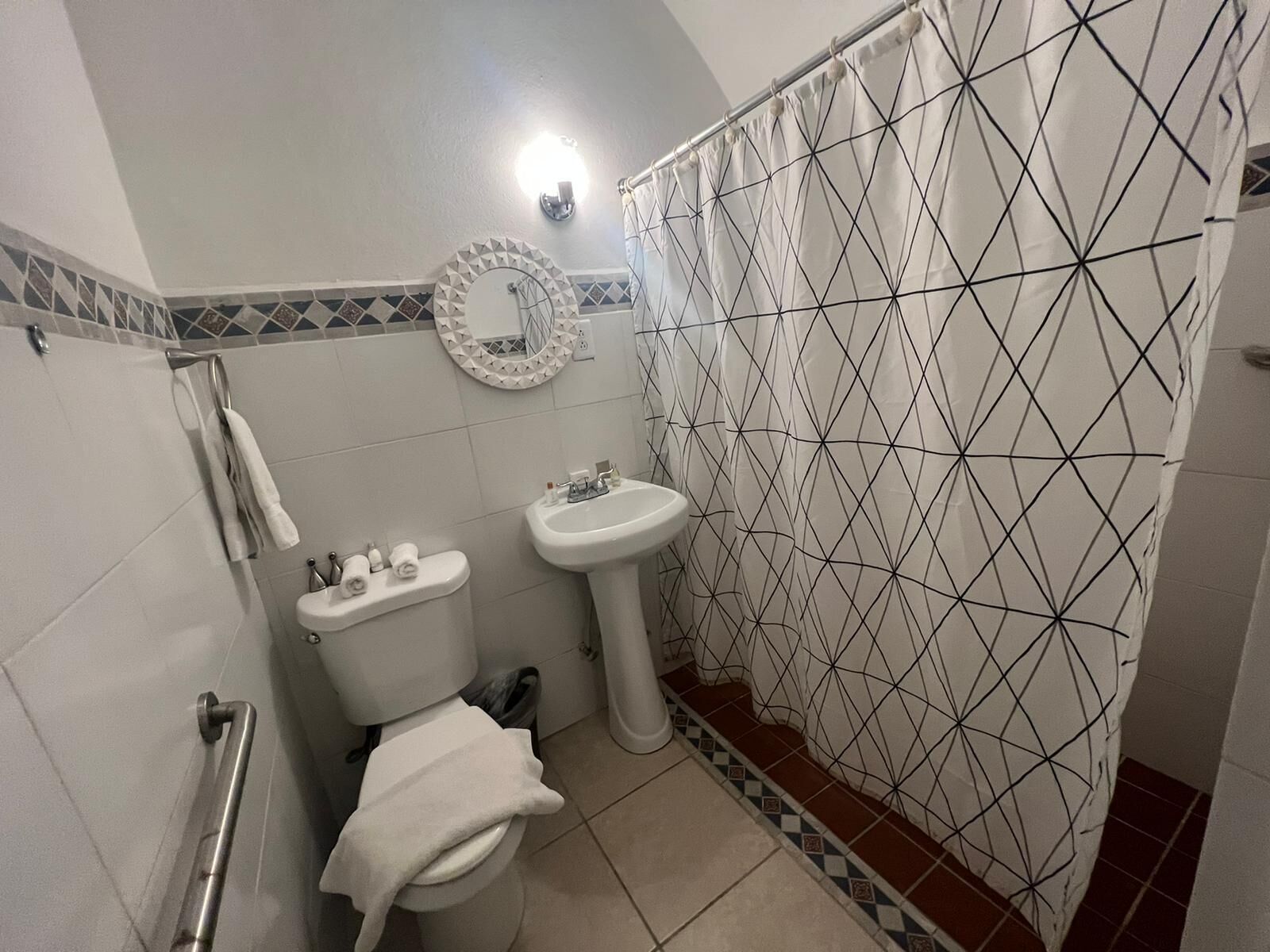 A bathroom with a toilet, sink, and shower curtain with a geometric pattern.