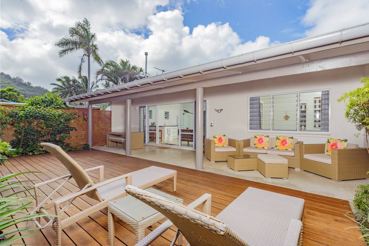 A modern house with a patio area featuring wicker furniture and a wooden deck.