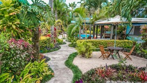A garden pathway leading to a seating area with a table and chairs. - Rarotonga Daydreamer Escape (Rarotonga)