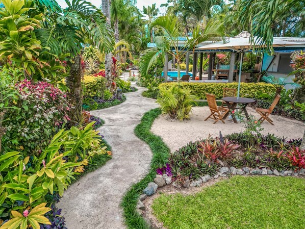 A garden pathway leading to a seating area with a table and chairs. - Rarotonga Daydreamer Escape (Rarotonga)
