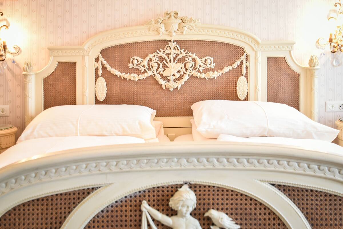 A bed with ornate headboard and decorative elements, including a statue and wall-mounted lights.