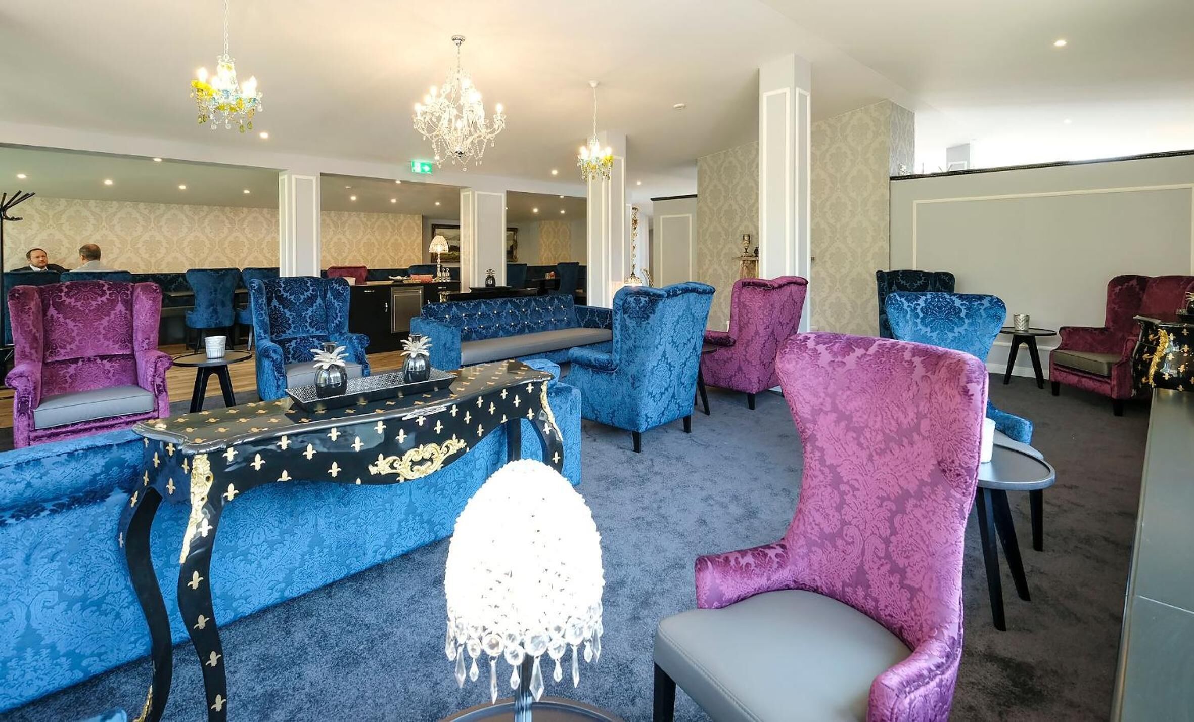 A spacious lounge area with multiple seating options, including sofas and armchairs, arranged around a central table.