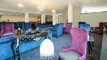 A spacious lounge area with multiple seating options, including sofas and armchairs, arranged around a central table.