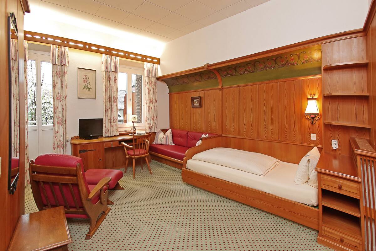A cozy room with a wooden bed, a desk with a chair, and a television.