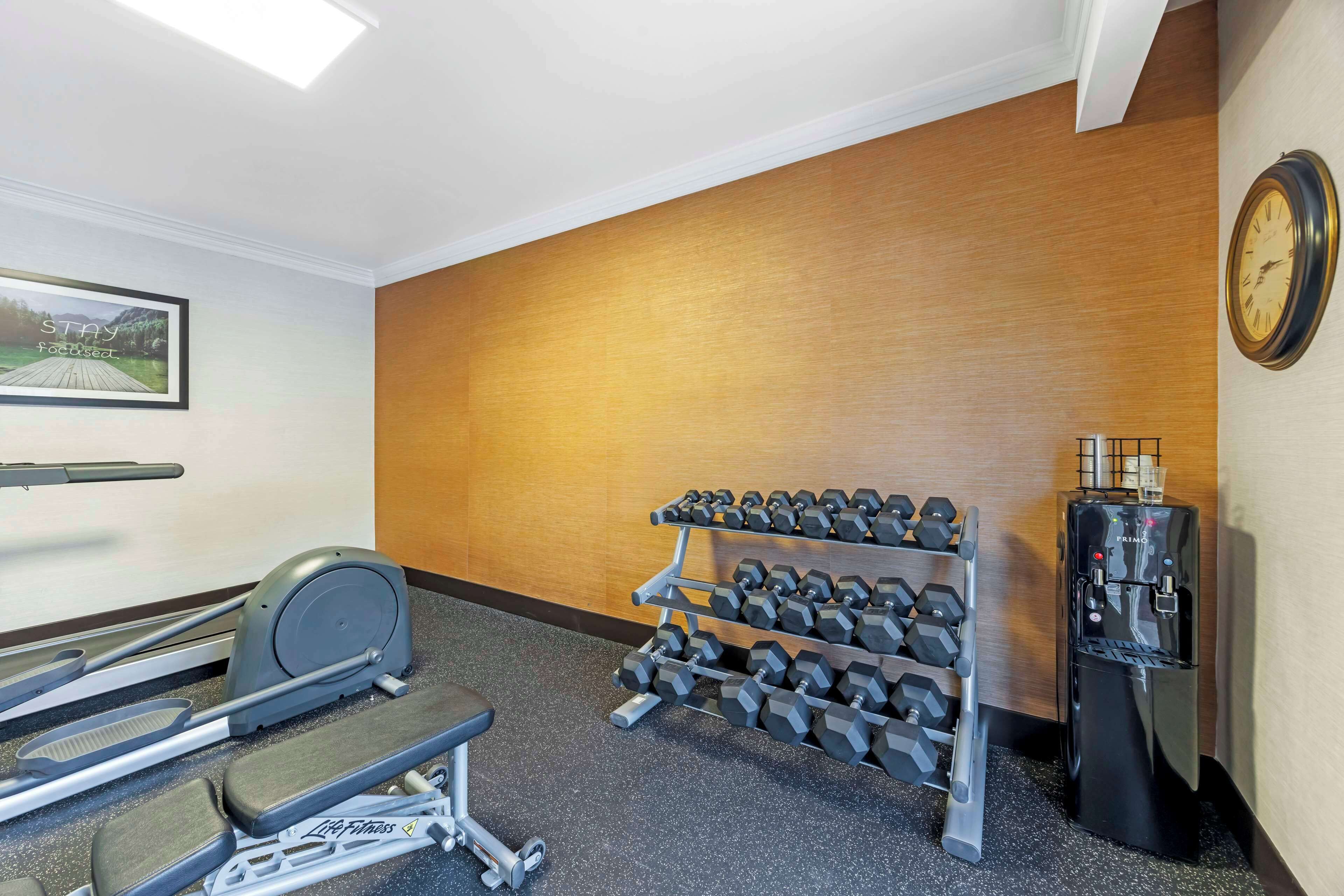 A gym with exercise equipment, a water dispenser, and a clock on the wall.