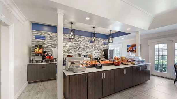 Un área de cocina moderna con una isla central, equipada con varios electrodomésticos y una estación de café.