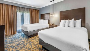 Habitación de hotel con dos camas, una mesita de noche, un teléfono y una alfombra estampada.