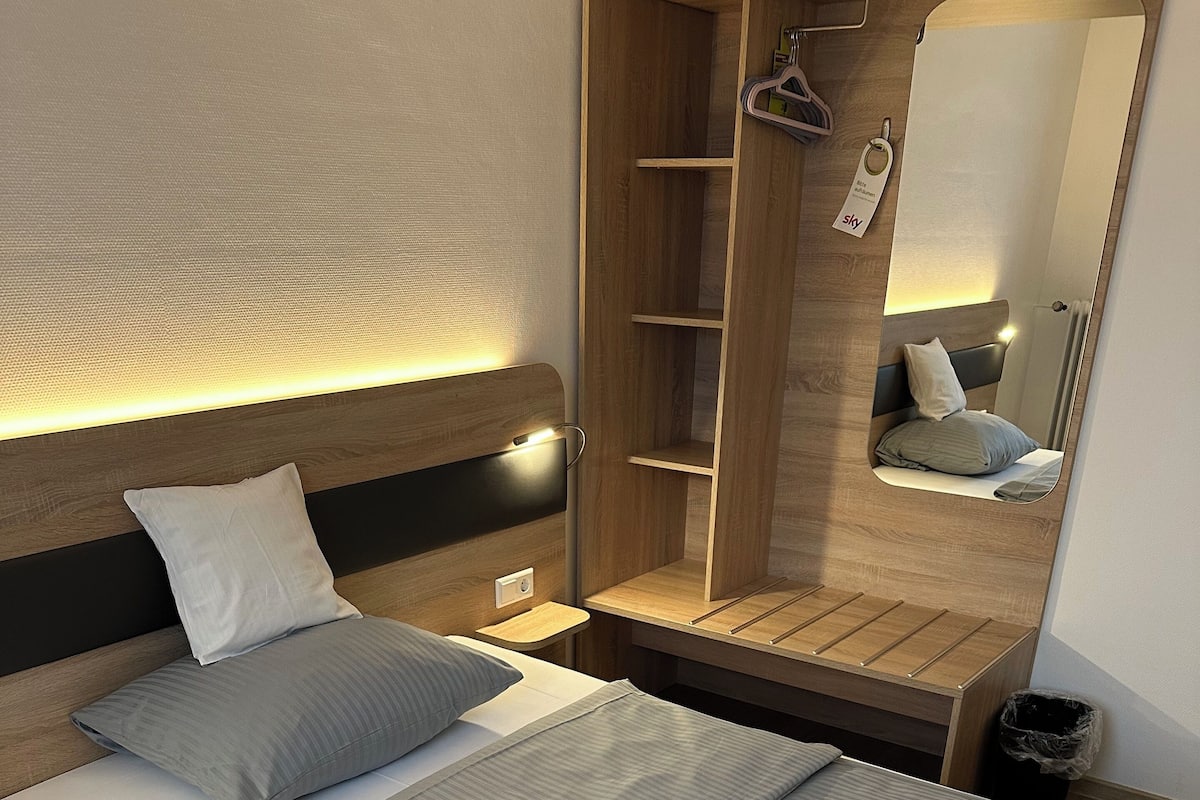 A modern bedroom with a bed, bedside tables, a wardrobe, and a mirror.