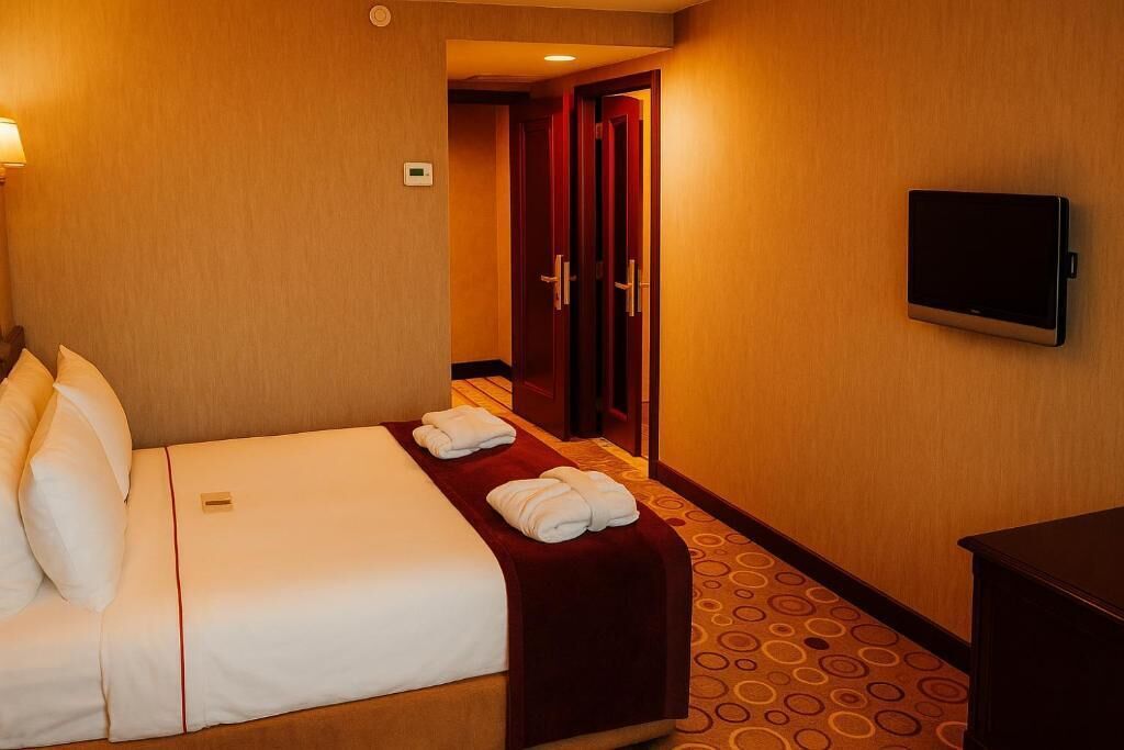 A hotel room with a bed, a TV, and a door leading to another room.