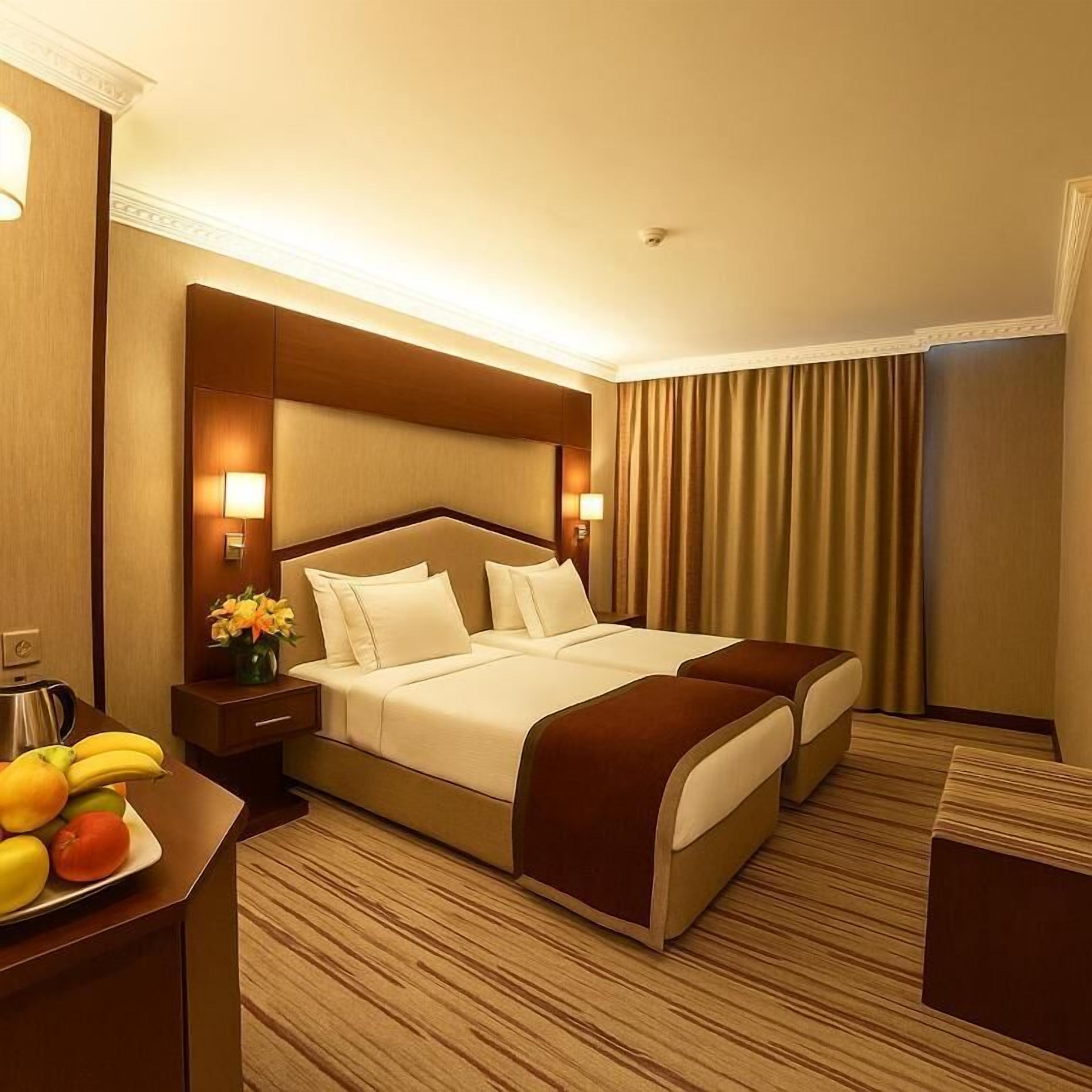 Une chambre d’hôtel avec un grand lit, deux tables de chevet, une petite table et un plancher en bois.
