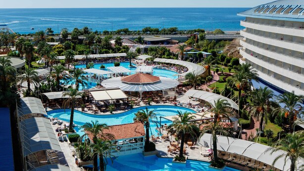 A resort with multiple swimming pools, palm trees, and a view of the ocean. - Crystal Admiral Aqua Collection - All inclusive (Manavgat)