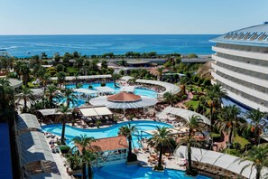 A resort with multiple swimming pools, palm trees, and a view of the ocean. - Crystal Admiral Aqua Collection - All inclusive (Manavgat)