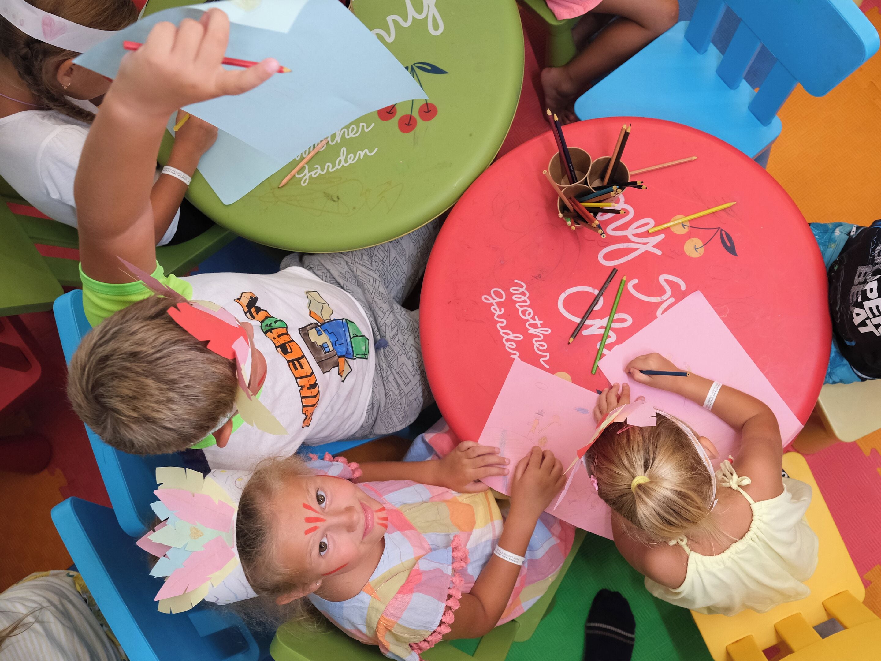 Children engaged in a craft activity with colorful chairs and tables.