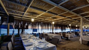 An outdoor dining area with tables set for two, overlooking a body of water. - Crystal Admiral Aqua Collection - All inclusive (Manavgat)