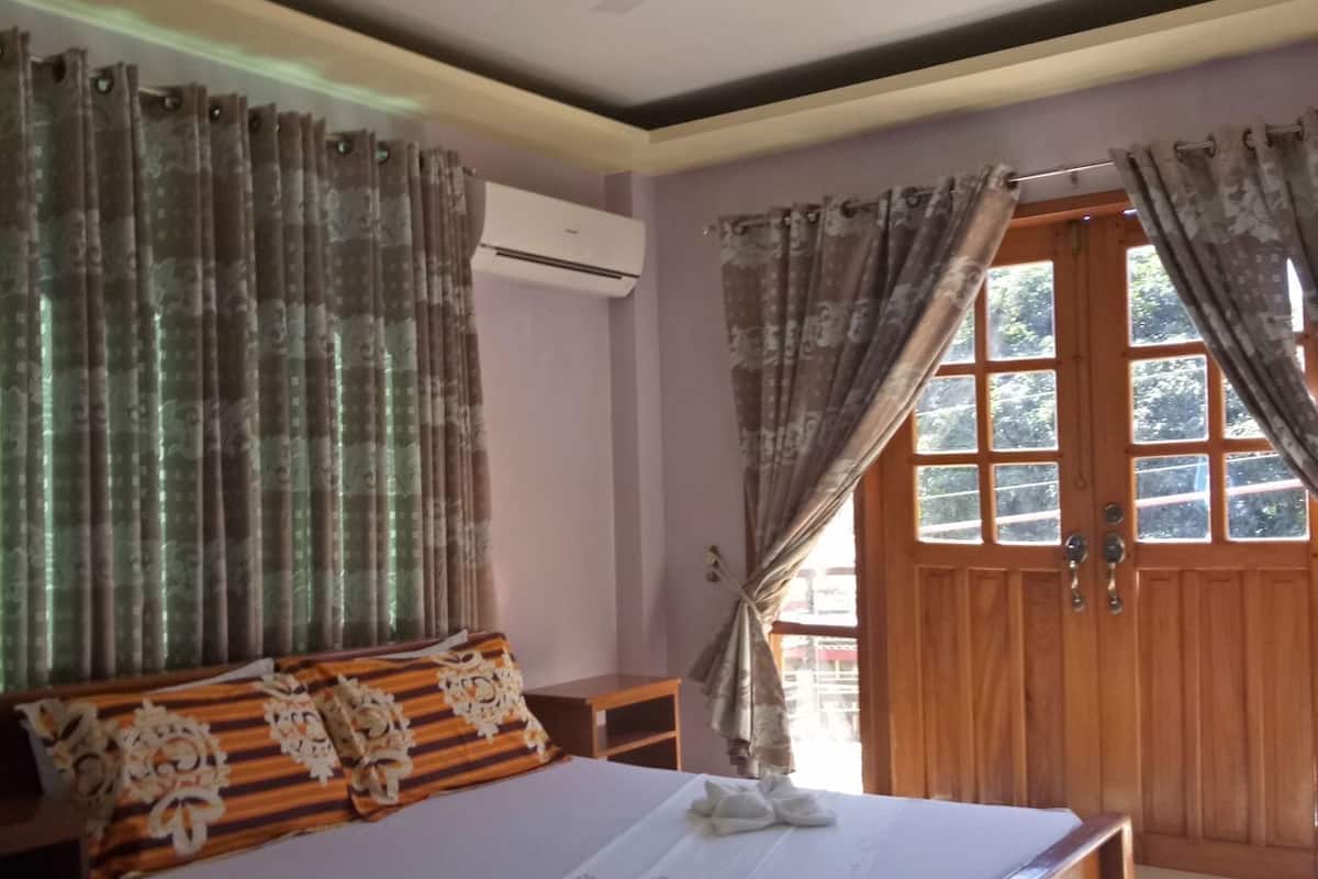 Ein Schlafzimmer mit einem Bett, einem Deckenventilator, einer Holztür und Vorhängen.