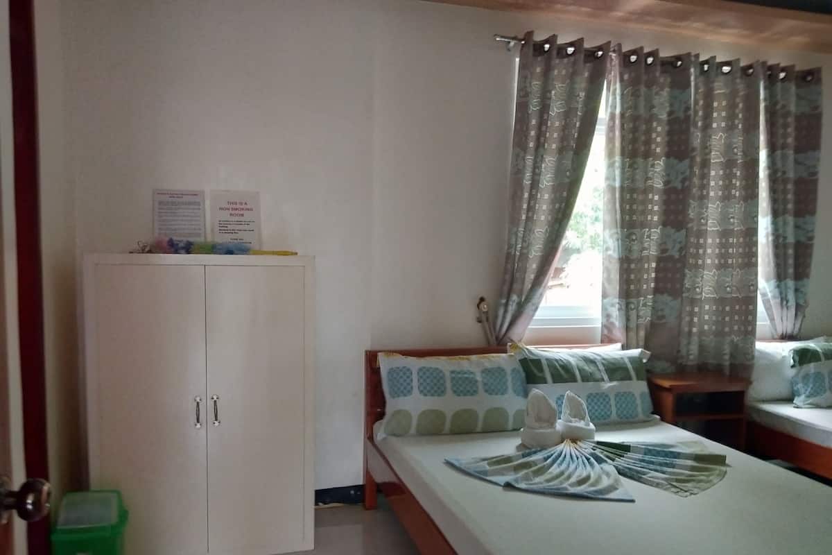 Ein Schlafzimmer mit einem Bett, einem Kleiderschrank, einer grünen Mülltonne und einem Fenster mit Vorhängen.