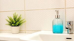 A bathroom with a white sink, a green potted plant, and a sign instructing to keep the bathroom clean.