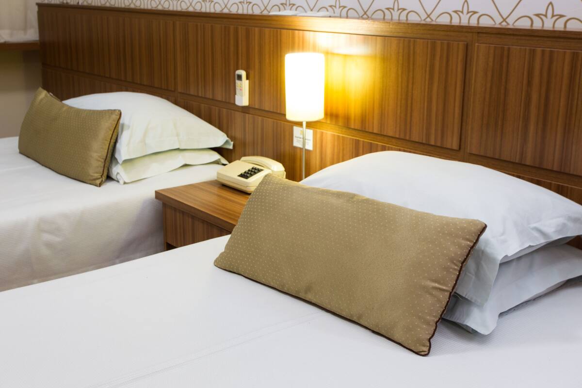 Une chambre d’hôtel avec deux lits, chacun étant équipé d’un oreiller et d’une table de chevet avec un téléphone.