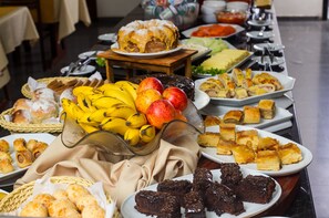 A buffet table with various food items including fruits, pastries, and desserts.