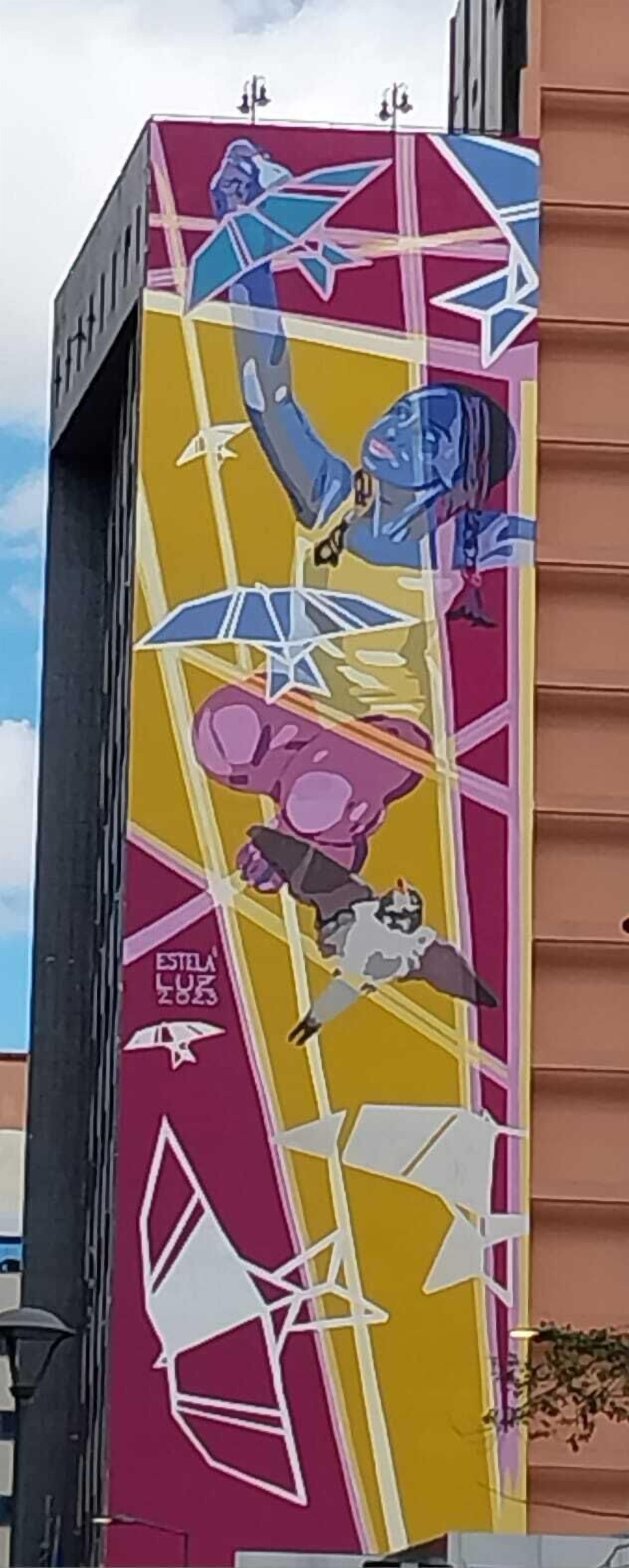 Un edifici amb un mural colorit que representa formes i figures abstractes.