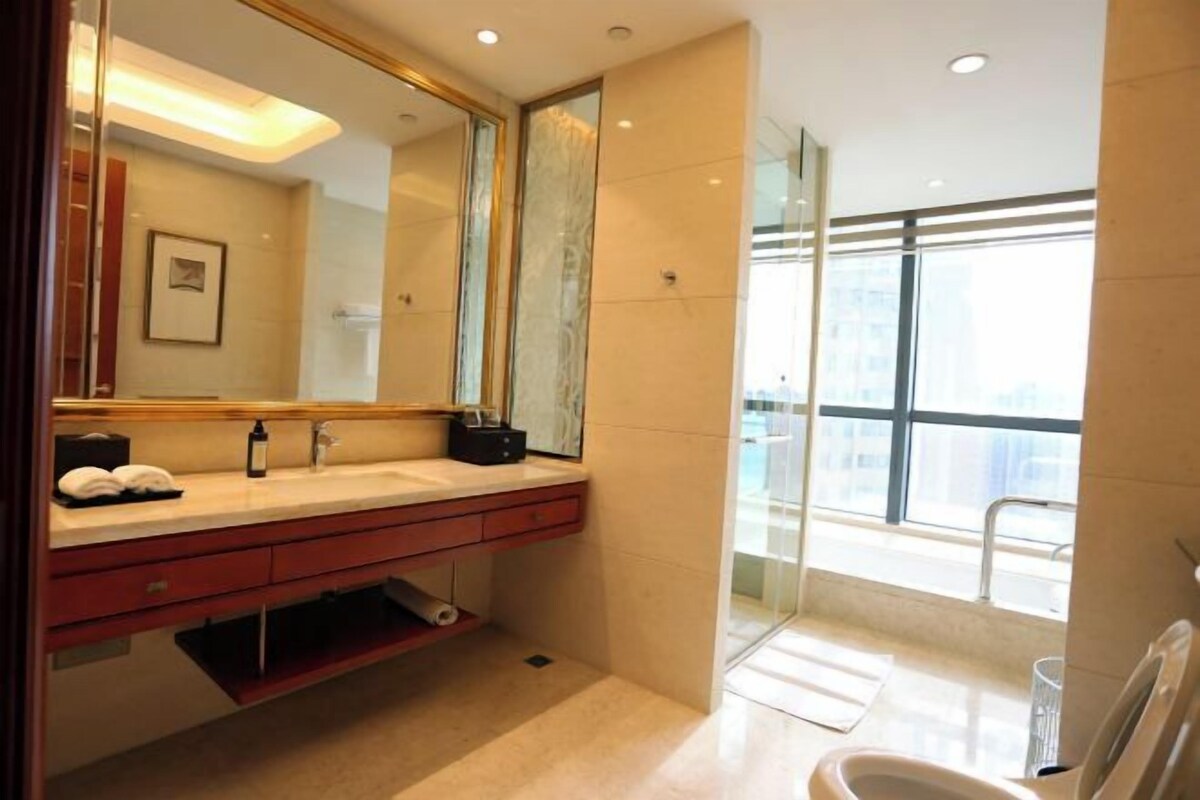 Un baño moderno con un espejo grande, un tocador con lavabo y una zona de ducha.