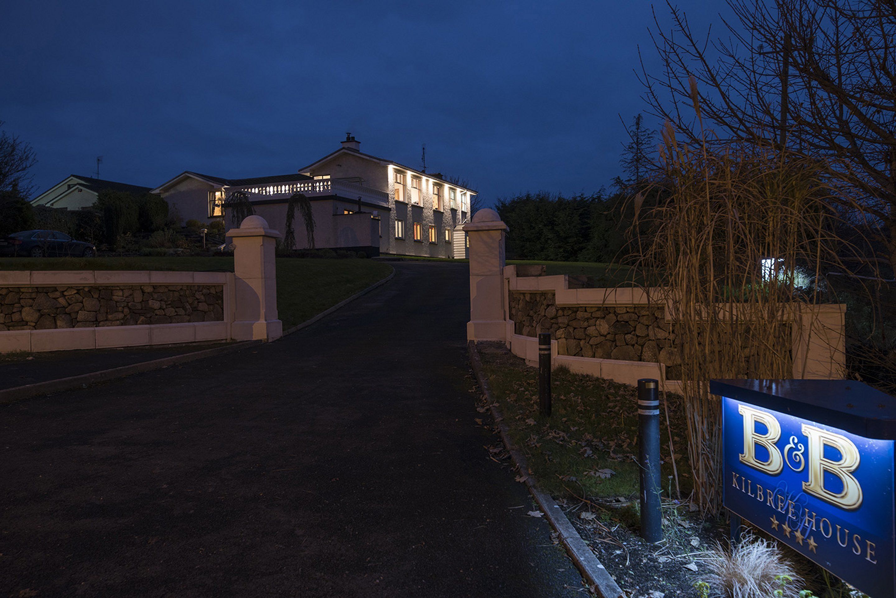 A large, well-lit house with a stone entrance and a sign reading "B&B Kilbre House".