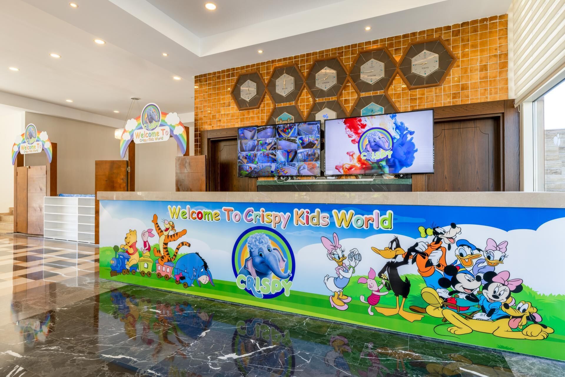 A reception area with a colorful mural, clocks, and a digital display.