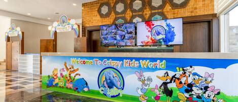 A reception area with a colorful mural, clocks, and a digital display.