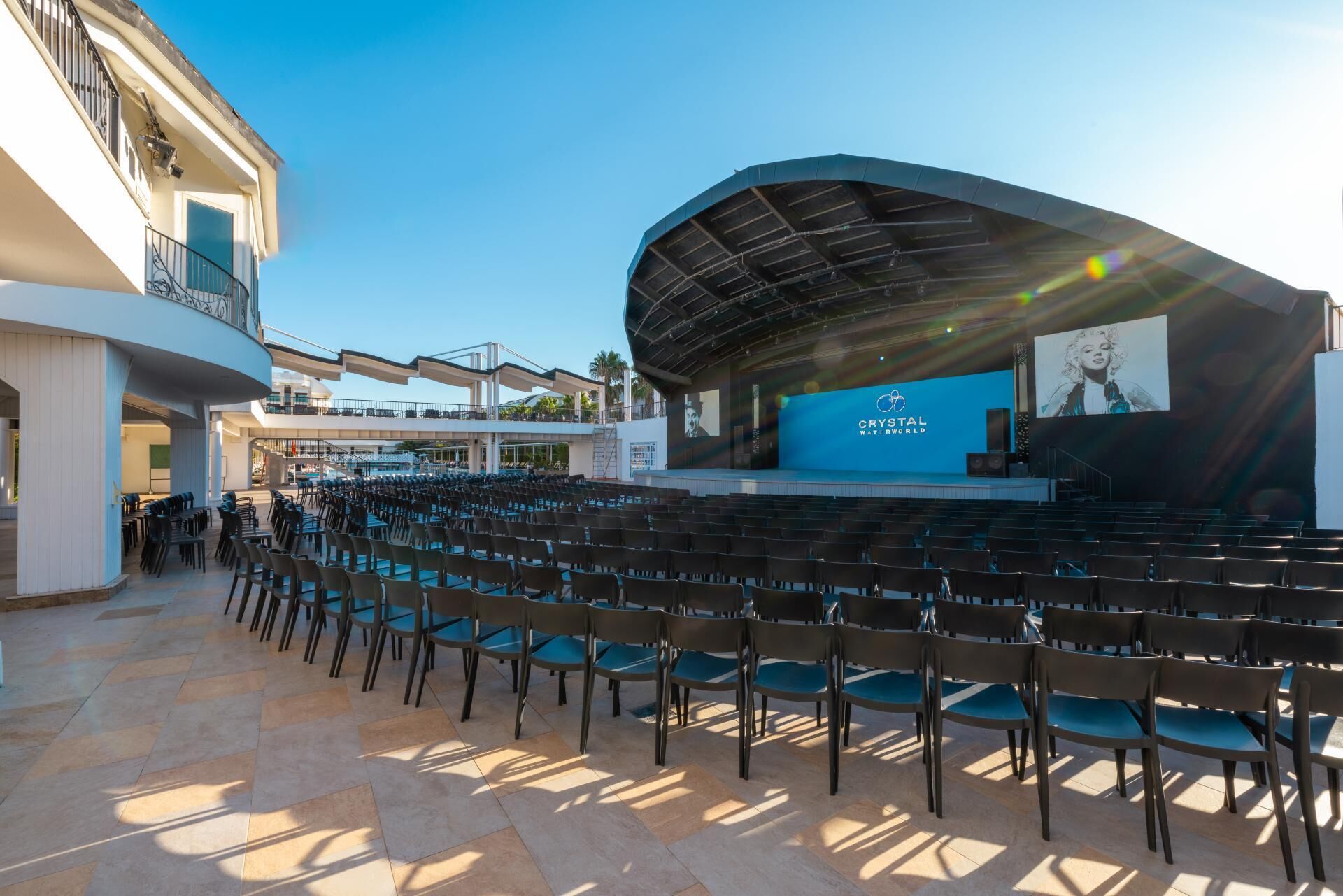 An outdoor amphitheater with rows of chairs, a stage, and a clear sky.