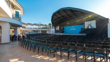 An outdoor amphitheater with rows of chairs, a stage, and a clear sky.