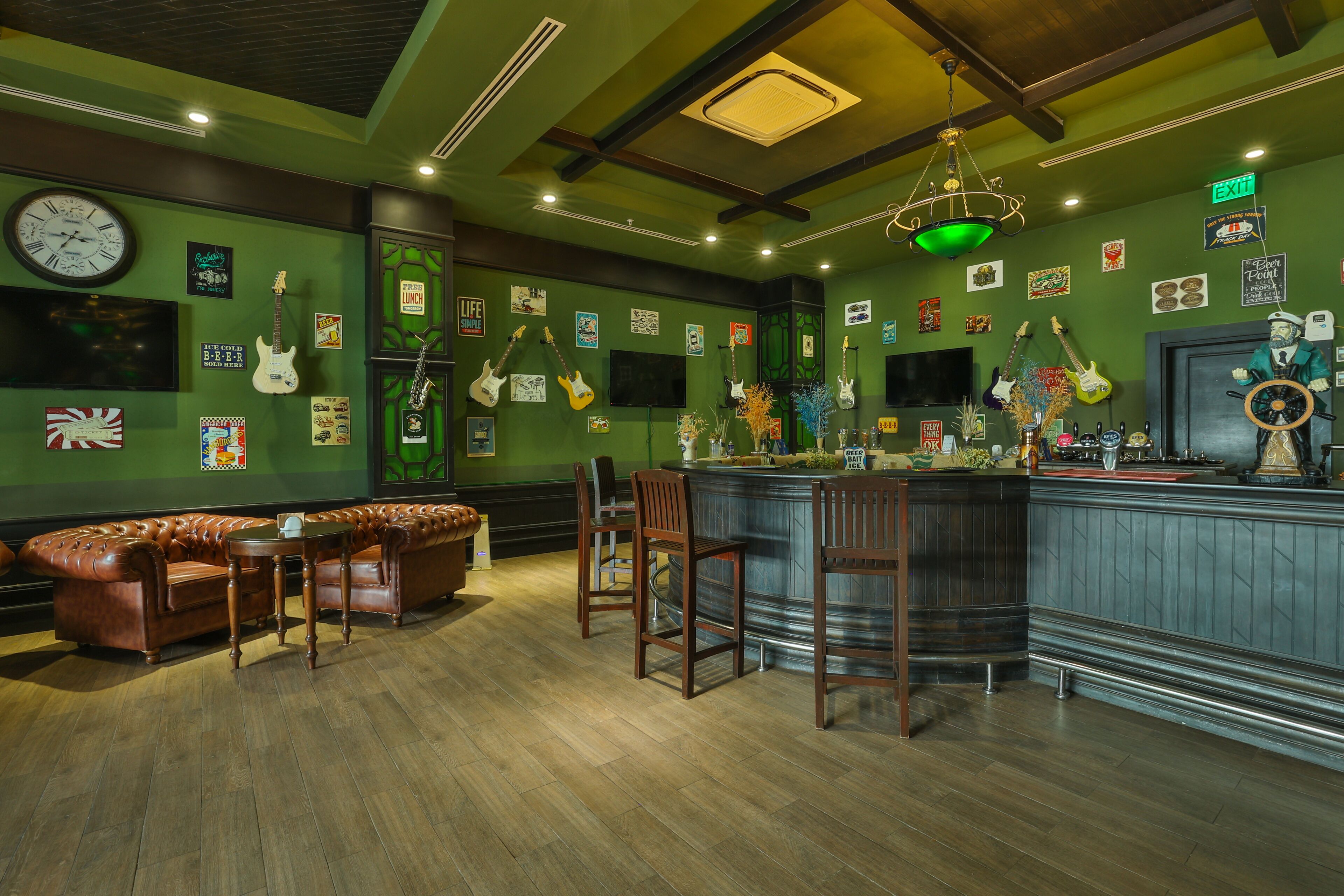 A bar area with a green wall, wooden furniture, and various musical instruments.