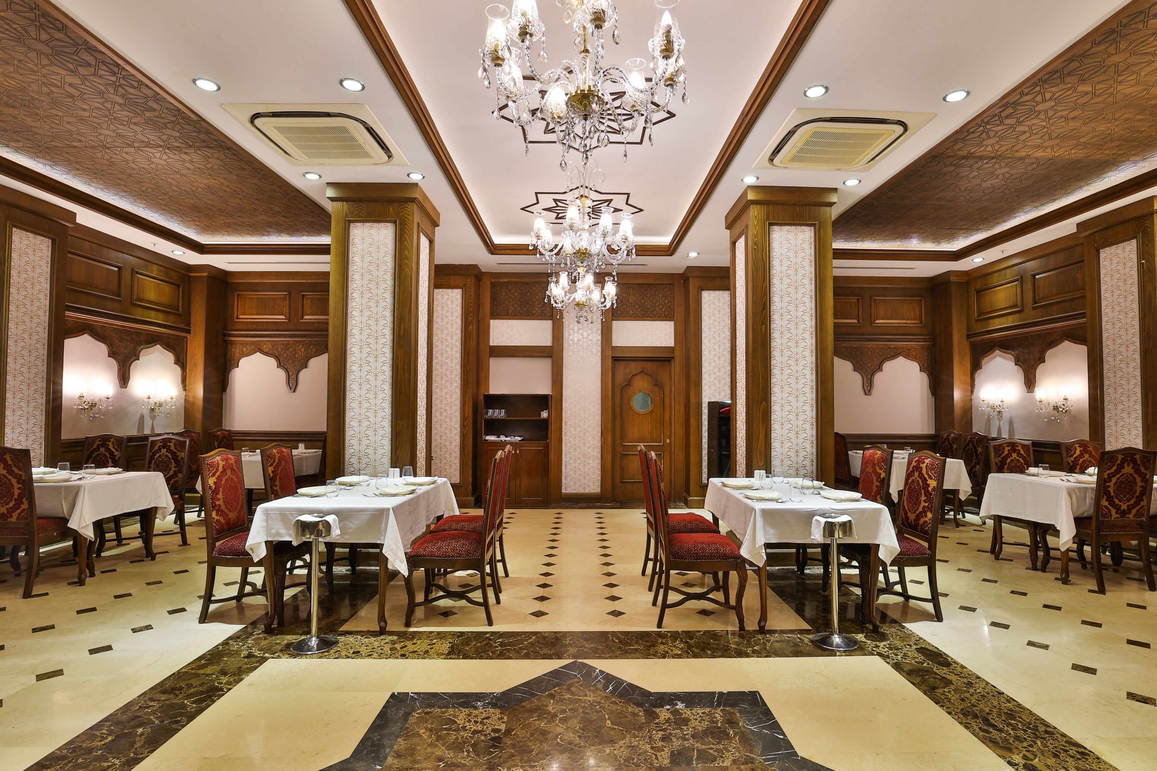 A formal dining room with tables, chairs, and a chandelier.
