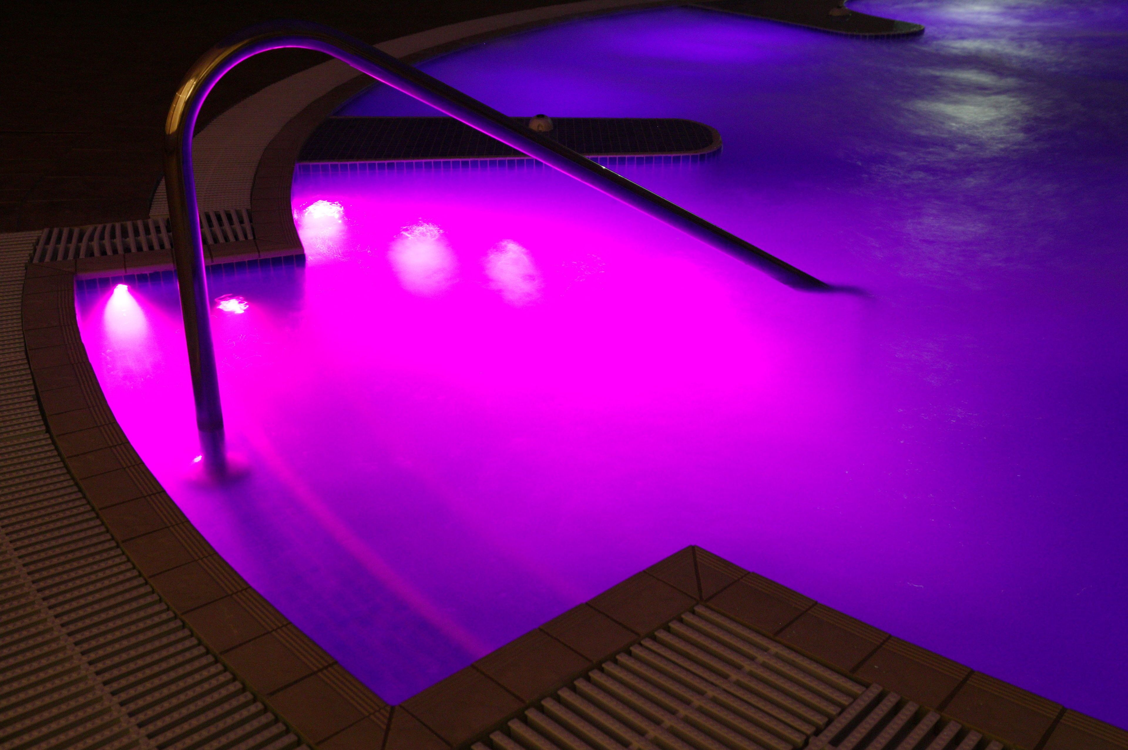 A swimming pool with a purple-lit edge and a modern design.