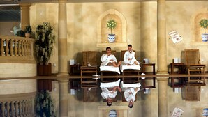 A hotel lobby with a reflective floor, wooden furniture, and potted plants. - Whittlebury Hall Hotel & Spa (Towcester)