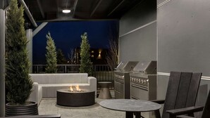 Un patio al aire libre con una fogata, asientos y una parrilla.
