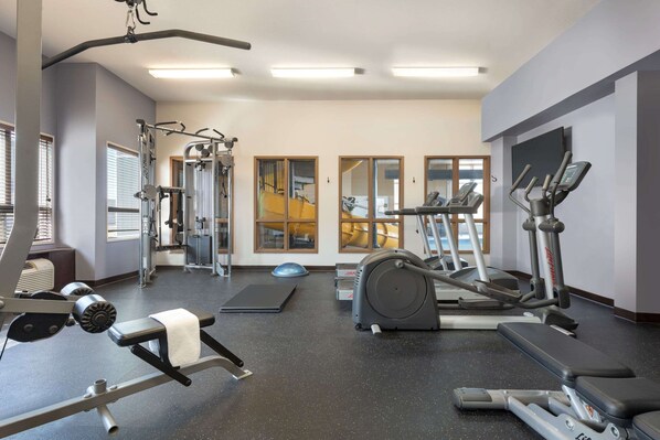 Une salle de sport équipée de divers appareils d’exercice, notamment des tapis de course, un vélo d’appartement et des appareils de musculation.