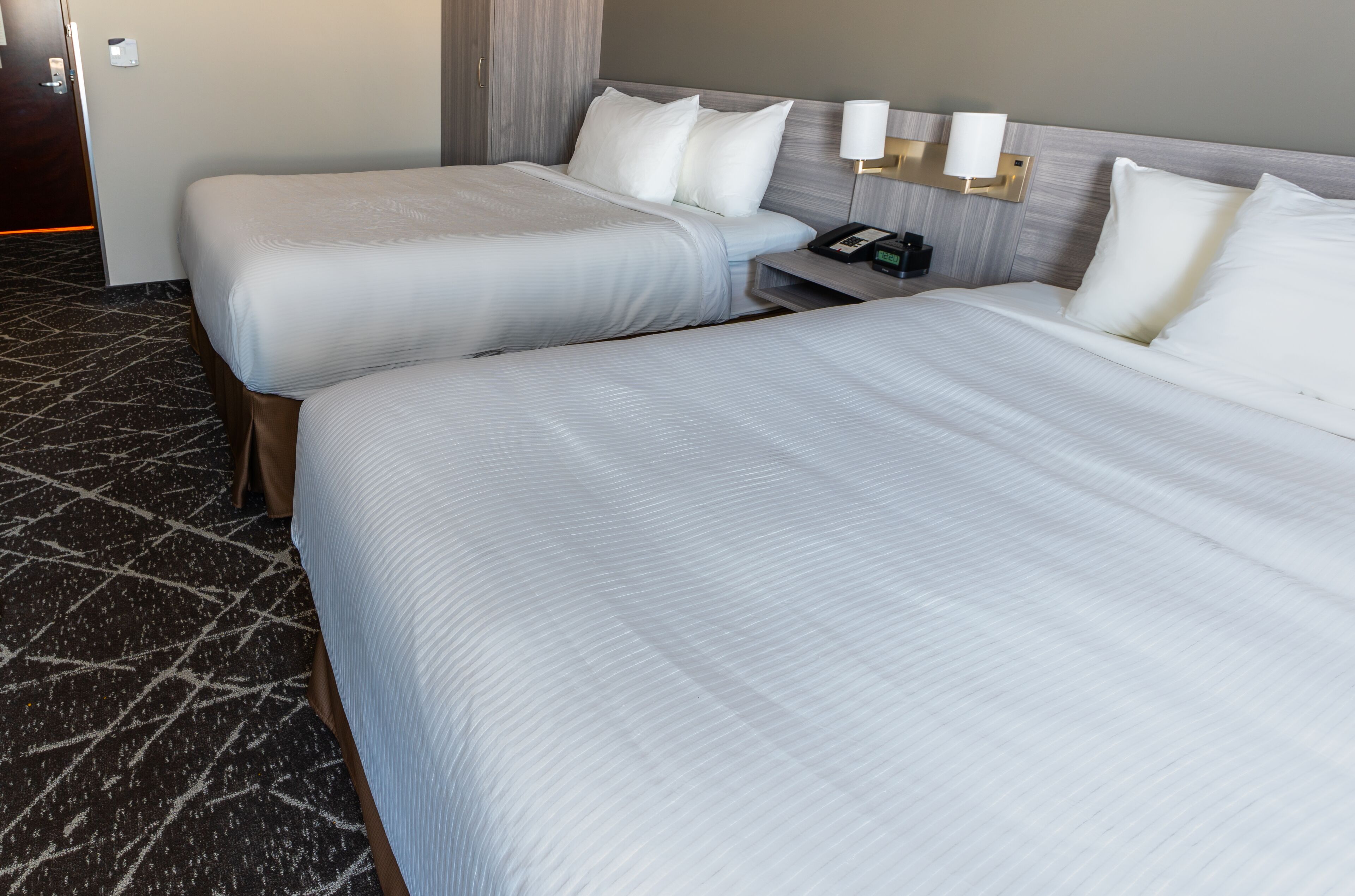 Ein Hotelzimmer mit zwei Betten, einem Nachttisch, einer Lampe und einem Telefon.
