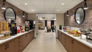 Un área de cocina moderna con una encimera larga, electrodomésticos integrados y un espacio de estar al fondo.
