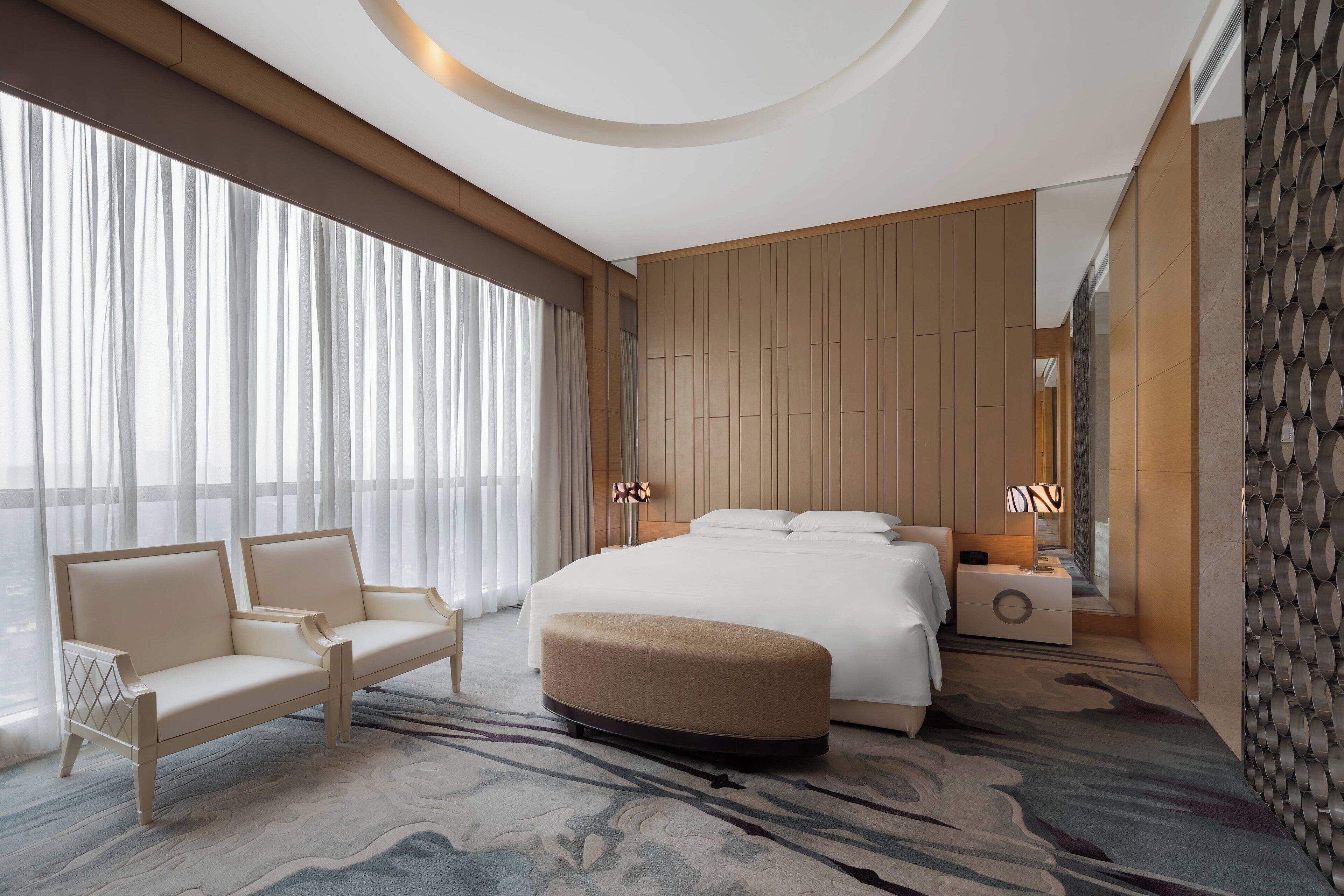 A modern hotel room with a large bed, a sofa, and a nightstand.