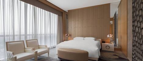 A modern hotel room with a large bed, a sofa, and a nightstand.