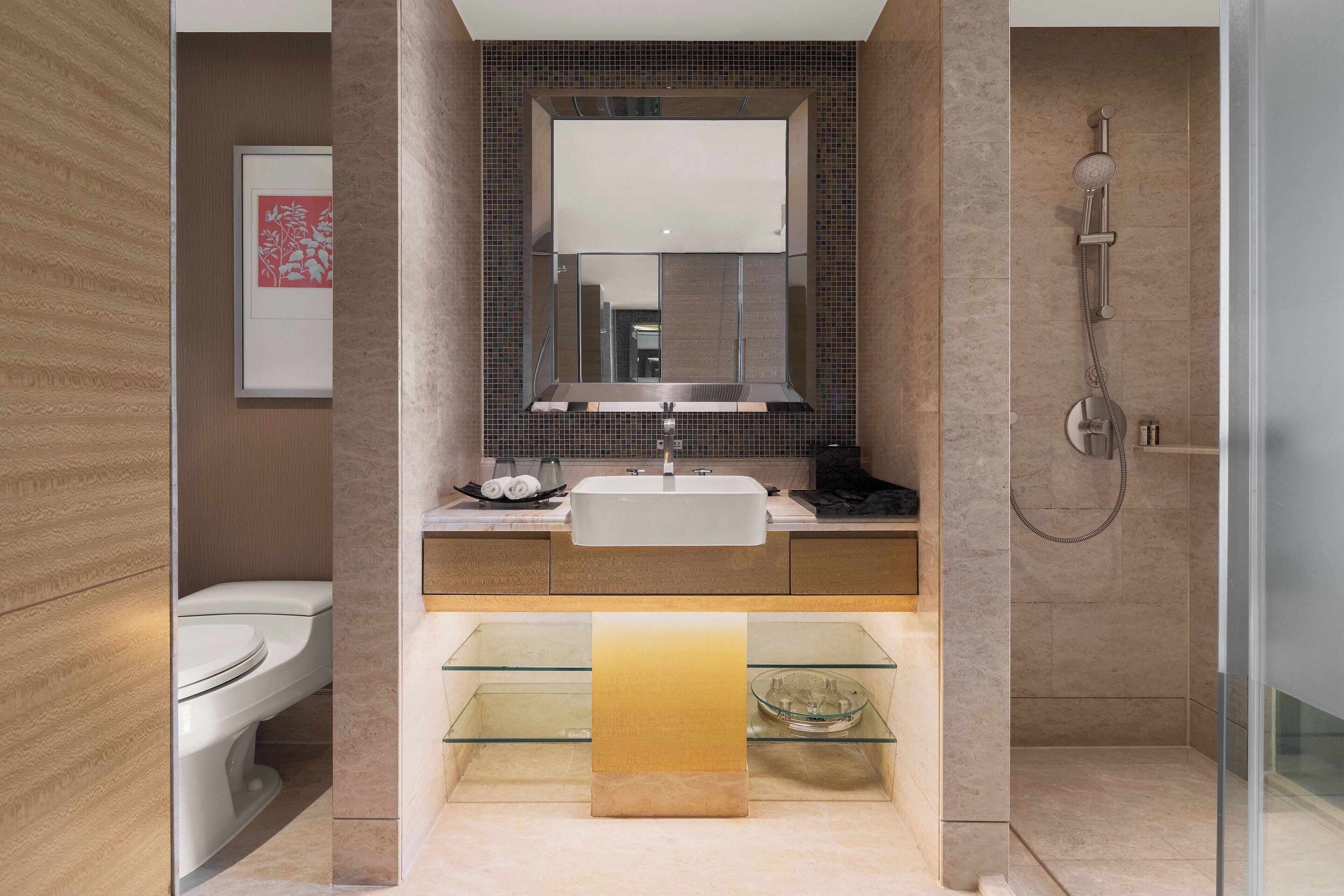 Une salle de bain moderne avec un grand miroir, un lavabo blanc, une étagère en verre et un espace douche.