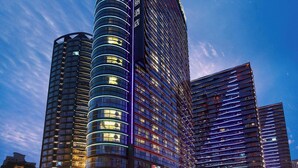 Een modern hotel met een gebogen gevel, meerdere verdiepingen en verlichte ramen.