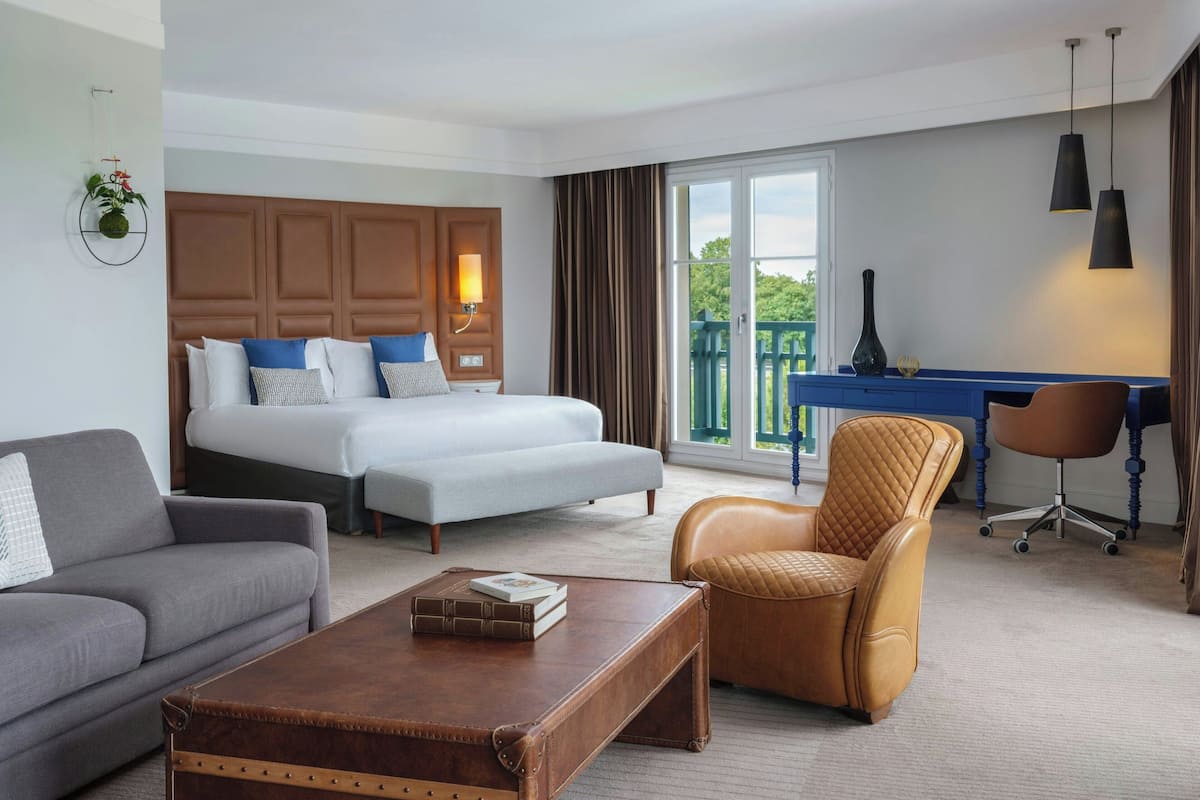 A hotel room with a bed, a sofa, a desk, and a chair.