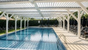 A swimming pool with a white pergola structure, surrounded by lounge chairs and umbrellas. - Renaissance Paris Hippodrome De St. Cloud Hotel (Rueil-Malmaison)