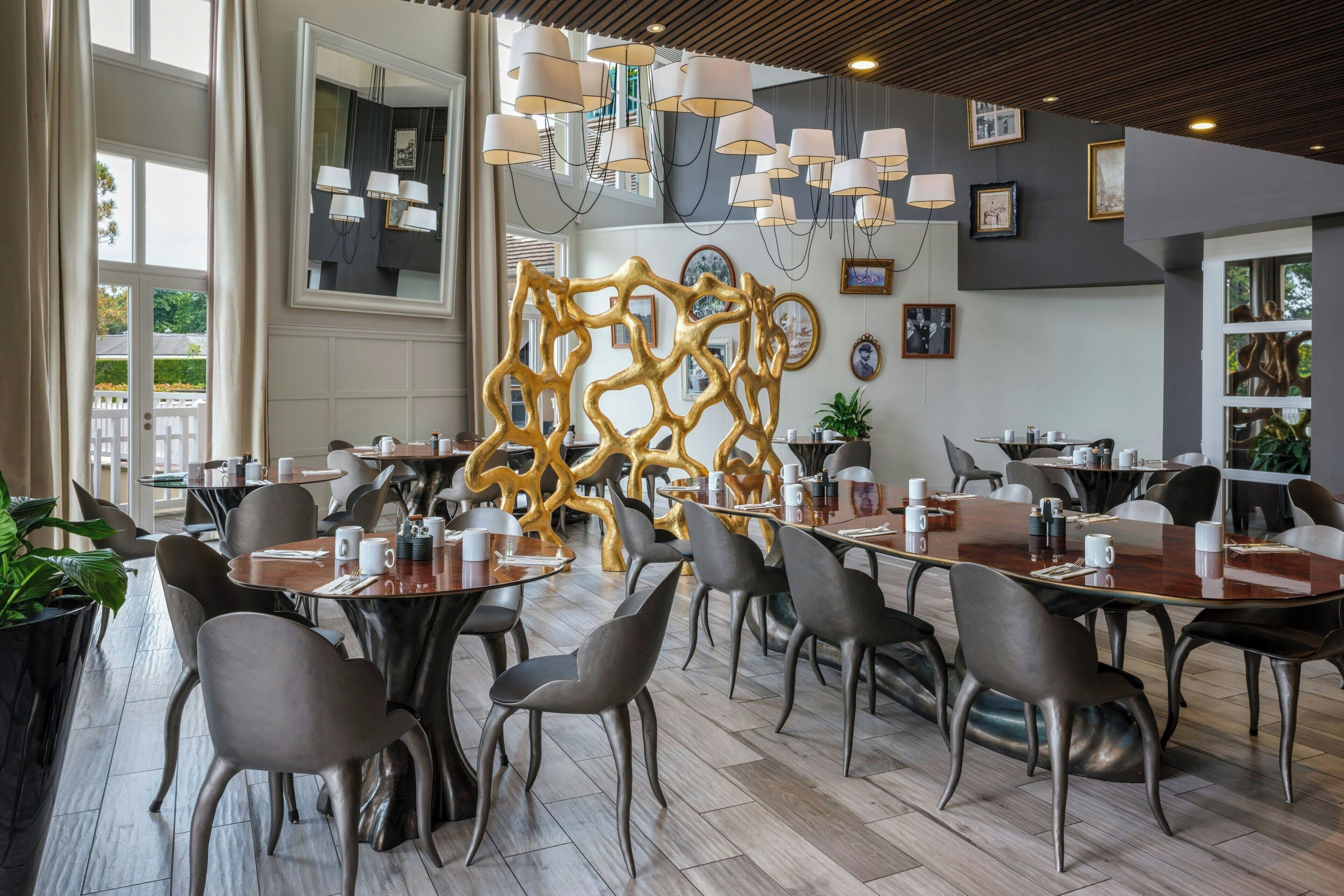 A modern dining area with round tables, grey chairs, and a decorative golden wall.