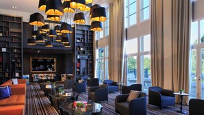 A spacious reading area with multiple seating options, large windows, and a central fireplace. - Renaissance Paris Hippodrome De St. Cloud Hotel (Rueil-Malmaison)