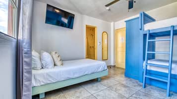 Um quarto com cama, beliche, ventilador de teto, televisão e porta.