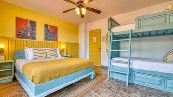 A room with a bed, bunk beds, a ceiling fan, and artwork on the wall.