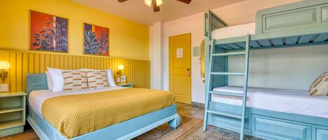 A room with a bed, bunk beds, a ceiling fan, and artwork on the wall.